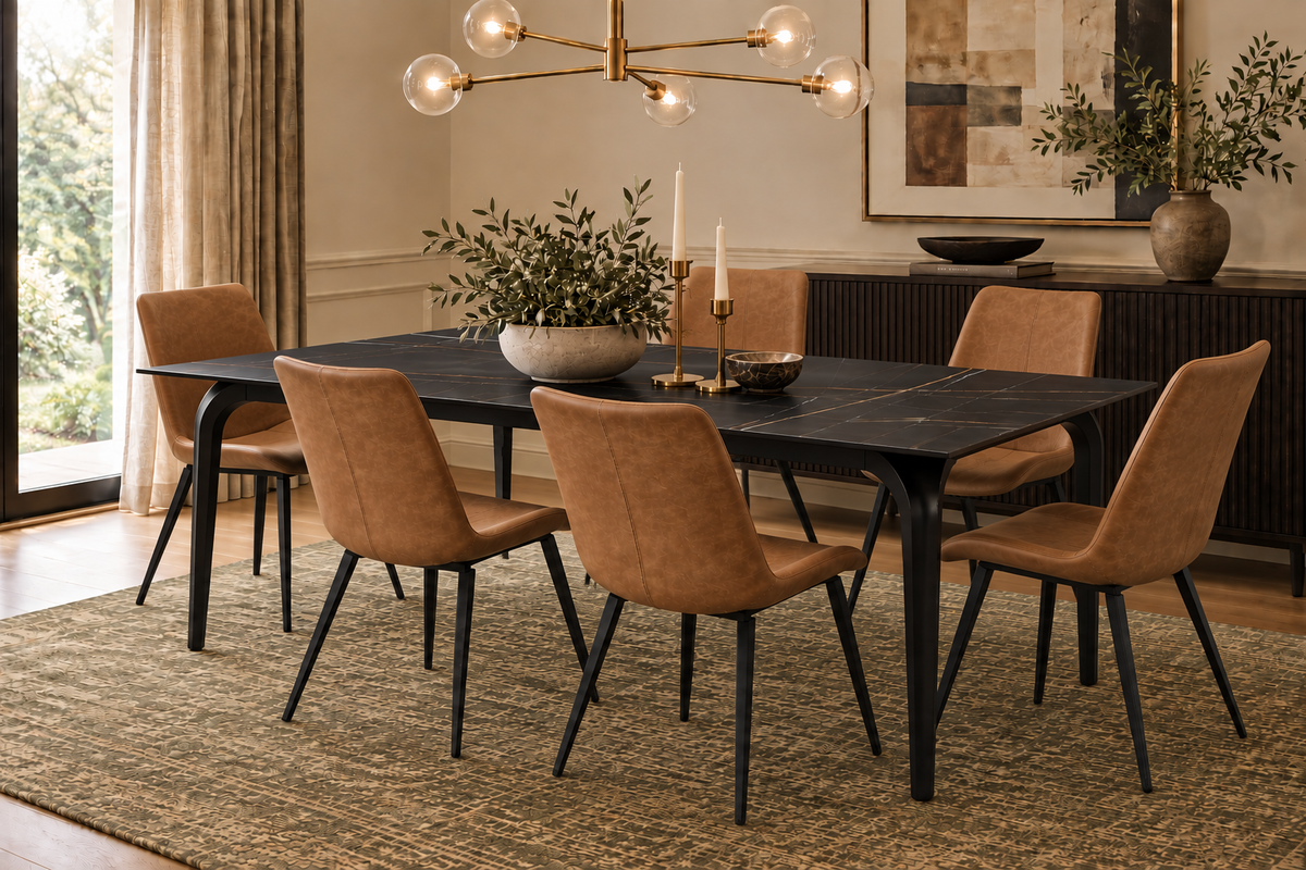 A modern dining room set featuring a rectangular black stone table with black metal legs and six upholstered chairs in a warm tan suede or velvet fabric with black legs, set on a textured beige rug.